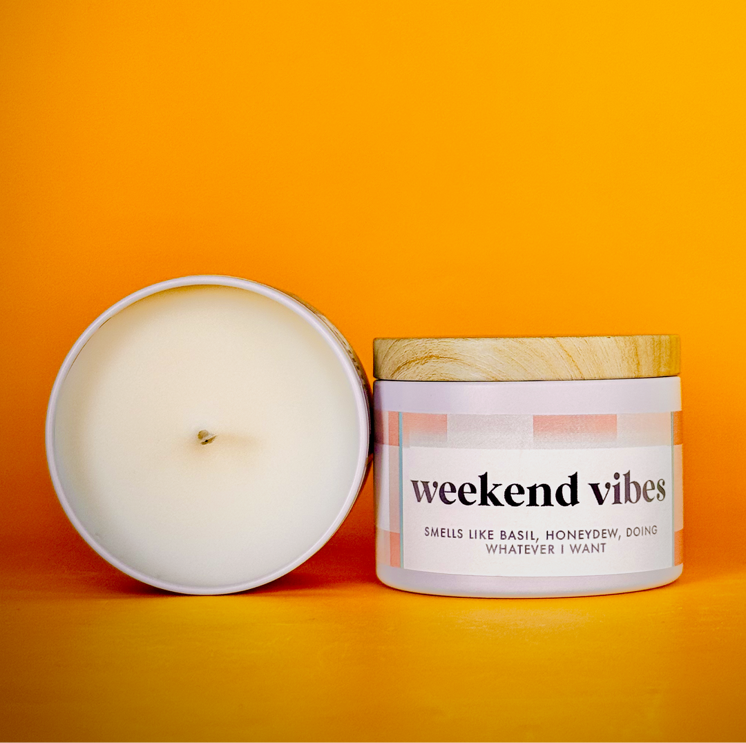 Candle and its packaging labeled 'weekend vibes' on an orange background